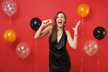 Bitcoin metal madeni para altın renkli, parlak kırmızı arka plan hava balonu üzerinde gelecek para birimi holding siyah elbise Yayilim eller çok memnun kadın. Mutlu yeni yıl, Doğum günü mockup tatil parti konsept