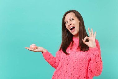 Örgü pembe kazaklı bakılması, dalgın genç kadın Ok jest, gösterilen tut elinde mavi turkuaz duvar arka plan stüdyo portre üzerinde izole kek. İnsanlar yaşam tarzı kavramı. Kopyalama alanı alay