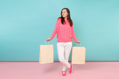 Tam uzunlukta örme gül kazaklı gülümseyen genç kadın portresi, beyaz parlak pembe mavi pastel duvar arka planda Studio izole poz pantolon. Moda yaşam tarzı kavramı. Kopyalama alanı alay