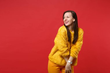 Bir kenara Studio parlak kırmızı duvar arka plan üzerinde izole sarı kürk kazak bakarak neşeli gülümseyen güzel genç kadın portresi. İnsanlar samimi duygular, yaşam kavramı. Kopyalama alanı alay
