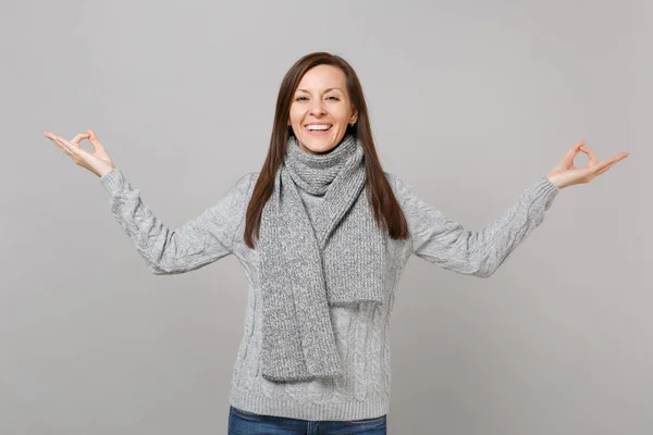 微笑的年轻女子在灰色毛衣 围巾举行瑜伽手势牵手 放松冥想隔离在灰色背景在工作室 健康时尚生活方式的人真诚的情绪寒冷的季节概念 — 图库照片