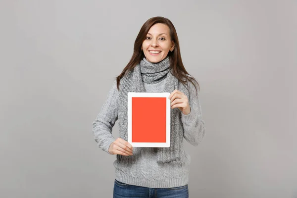 灰色のセーターの女性を笑顔スカーフは 灰色の背景に分離された空白の空の画面とタブレット コンピューターを保持します 健康的なライフ スタイル オンライン治療の寒い季節の概念をコンサルティングします コピー スペースをモックアップします — ストック写真