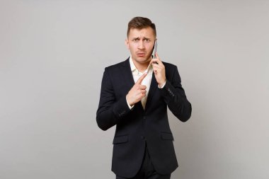 Gri arka plan üzerinde izole konuşma iletken siyah takım elbise işaret parmağı cep telefonda konuşurken ilgili iş adamı. Başarı kariyer servet iş kavramı. Kopyalama alanı alay