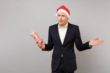 Noel şapkalı şaşkın iş adamı tutun plastik bardak kola gri arka plan üzerinde izole el yayılıyor. Başarı kariyer servet iş. Mutlu yeni yıl 2019 kutlama tatil parti konsept