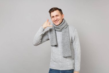 Gri süveterli adam gülümsüyor, eşarp gibi telefon jest yapıyor gri arka plan üzerinde bana geri izole çağrı diyor. Sağlıklı moda yaşam tarzı, insanlar samimi duygular, soğuk sezon kavramı. Kopyalama alanı alay