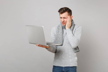 Gri kazak, dizüstü pc bilgisayar, çalışma eşarp genç adam el baş üzerinde izole gri arka plan üzerine koyarak bitkin. Sağlık, online tedavi soğuk sezon kavramı danışmanlık. Kopyalama alanı alay