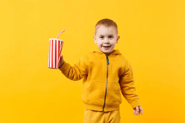 小乐趣开朗的男孩 穿着黄色衣服举行一杯苏打水隔离在橙色的墙壁背景 儿童工作室肖像 童年生活方式的概念 模拟复制空间 — 图库照片