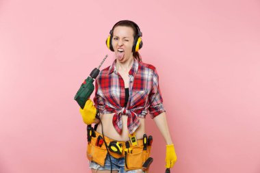 Enerji seksi tamirci kadın eldiven, gürültü yalıtımlı kulaklıklar, Seti Araçları, pembe arka plan izole elektrikli matkap tutan araçların tam kemer. Kadın erkek iş. Yenileme kavramı