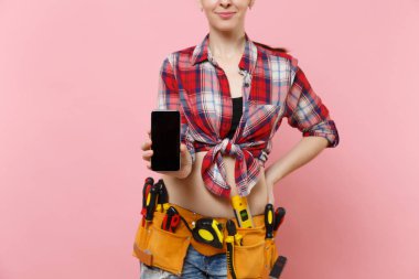 Kit araçları kemer gösteren kamera cep telefonu, pembe arka plan izole boş siyah Boþ ekran ekran dokunmatik ekran ile tutarak araçların tam olan kadın. Kadın erkek iş. Yenileme kavramı