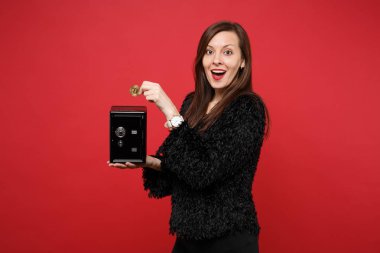 Metal banka para biriktirme, bitcoin, kırmızı zemin üzerine izole gelecek para birimi için güvenli tutarak kürk kazaklı genç kadın hayran. İnsanlar samimi duygular, yaşam kavramı. Kopyalama alanı alay