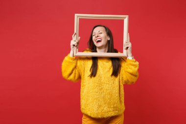 Genç kadın ile sarı kürk süveterli gülen portre Studio kırmızı duvar arka plan üzerinde izole resim çerçevesi tutan gözler kapalı. İnsanlar samimi duygular, yaşam kavramı. Kopyalama alanı alay