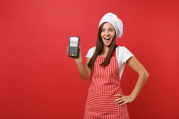 Housewife female chef cook or baker in striped apron t-shirt toque chefs hat isolated on red wall background. Woman hold in hand wireless bank payment terminal nfc device. Mock up copy space concept