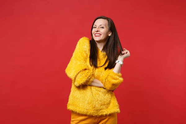 微笑的画像惊艳美丽的年轻女子在黄色毛皮毛衣站立在明亮的红色墙壁背景在演播室孤立 人们真诚的情感 生活方式的理念 模拟复制空间 — 图库照片