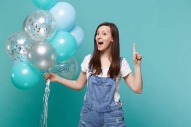 Genç kadın işaret parmağı harika yeni fikir, kutlama, izole mavi turkuaz duvar arka plan üzerinde renkli hava balonları holding ile hayran. Doğum günü tatil partisi, insanların duyguları kavramı