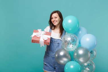 Hediye izole mavi turkuaz arka plan üzerinde renkli hava balonları ile şerit kutlama ile genç kadın tutun kırmızı şeritli mevcut kutusu gülümseyerek. Sevgililer günü, kadınlar günü, Doğum günü, tatil kavramı