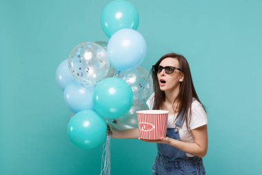 3d gözlük kova patlamış mısır renkli hava balonları ile kutluyor tutun film film izlerken şok kadın mavi turkuaz arka plan üzerinde izole. Doğum günü tatil partisi, sinema kavramı duygular