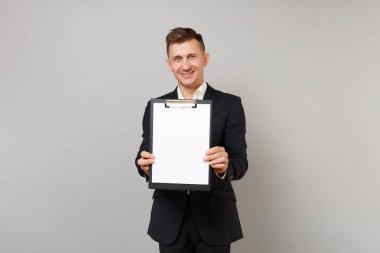 Klasik siyah elbiseli çekici genç iş adamı, gömlek gri arka plan üzerinde izole boş boş sayfası çalışma alanı ile pano tutun. Başarı kariyer servet iş kavramı. Kopyalama alanı alay