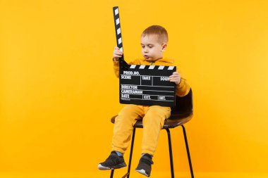 Küçük çocuk çocuk 3-4 yıl eski turuncu duvar arka planda, çocuk stüdyo portre izole sarı giysili. İnsanlar çocukluk yaşam tarzı kavramı. Elini tut Klaket yapım film. Kopyalama alanı alay