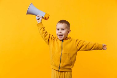 Küçük eğlenceli çocuk 3-4 yıl eski holding, elektronik megafon turuncu duvar arka planda, çocuk stüdyo portre izole konuşan sarı giysili evlat. İnsanlar çocukluk kavramı. Kopyalama alanı alay