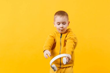 Küçük çocuk çocuk 3-4 yıl Kulaklık sarı elbise giyen eski turuncu duvar arka planda, çocuk stüdyo portre izole. İnsanlar samimi duygular çocukluk yaşam tarzı kavramı. Kopyalama alanı alay