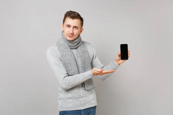 Młody Człowiek Szary Sweter Szalik Ręce Wskazując Telefon Komórkowy Puste — Zdjęcie stockowe