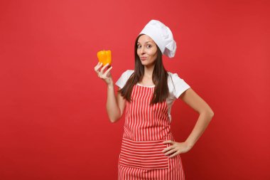 Ev hanımı kadın şef aşçı ya da baker Studio kırmızı duvar arka plan üzerinde izole çizgili önlük, beyaz tişört, toque şefler şapkalı. Gülümseyen kadın tutun el sarı biber. Kopyalama alanı kavramı alay