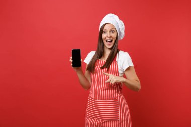 Ev hanımı kadın şef aşçı ya da çizgili önlük t-shirt toque şefler şapkalı kırmızı duvar arka plan üzerinde izole baker. Kadın cellphone yükselme içerik için boş ekran ile tutun. Kopyalama alanı kavramı alay