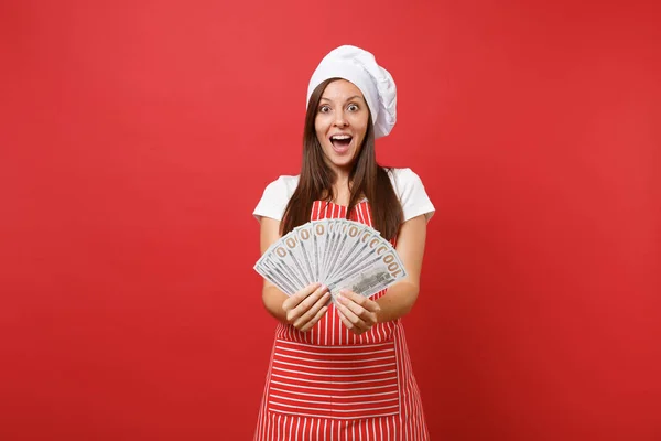 Ev hanımı kadın şef aşçı baker izole kırmızı duvar arka plan üzerinde çizgili önlük, beyaz tişört, toque şefler şapkalı. Dolar banknot bir sürü nakit para tutan mutlu kadın. Kopyalama alanı kavramı alay