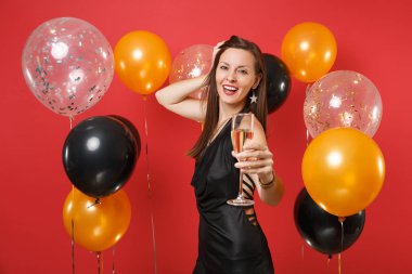 Siyah elbiseli Genç kız sevimli kutlamak, parlak kırmızı arka plan hava balonu üzerinde fotoğraf makinesinde şampanya eliyle işaret. Kadınlar günü, mutlu yeni yıl, Doğum günü mockup tatil parti konsept