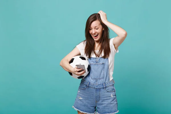 ターコイズ ブルーの壁の背景に分離した頭に手を置いて Sms メッセージを入力して 携帯電話を使用してサッカー ボールで陽気な若い女の子のフットボールのファン 人の感情 スポーツ家族レジャー コンセプト — ストック写真
