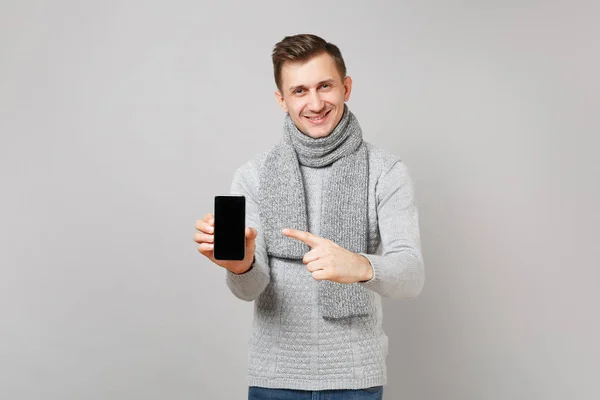 Uśmiechnięty Mężczyzna Szary Sweter Szalik Palec Wskazujący Telefon Komórkowy Puste — Zdjęcie stockowe