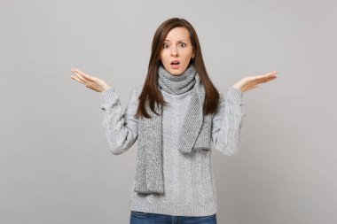 Gri kazak atkı Studio gri duvar arka plan üzerinde izole eller yayılan şok şaşkın genç kadın. Sağlıklı moda yaşam tarzı insanların samimi duygular soğuk sezon kavramı. Kopyalama alanı alay