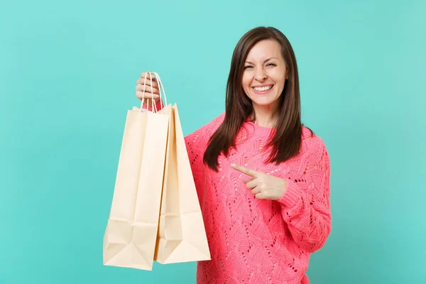 青の背景に分離の手で買い物をした後に購入するとパッケージ袋に人差し指を指しているピンクのニットのセーターに笑顔の若い女性 のライフ スタイルのコンセプトです コピー スペースをモックアップします — ストック写真