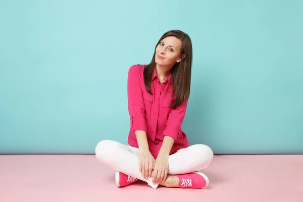 全长纵向微笑的年轻女子在玫瑰衬衫衬衫 白色裤子坐在地板上查出明亮的粉红色蓝色柔和的墙壁背景工作室 时尚生活概念模拟复制空间 — 图库照片