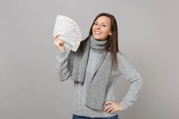微笑的年轻女子穿着灰色毛衣 围巾持有大量的美元钞票现金孤立在灰色背景 工作室肖像 健康时尚生活方式的人的情绪 寒冷的季节概念 — 图库照片