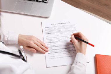 «Ana sayfa» kadın doktor hastanede tıbbi belgeleri doldurma çalışma masasında siting kapalı pastel pembe duvar arka plan izole görünümü. Tıbbi elbisesi stetoskop kadında. Sağlık Tıp kavramı