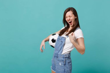 Çığlık atan genç kadın futbol fan neşelen destek favori takım ile futbol topu yumruk gibi mavi turkuaz duvar arka plan üzerinde izole kazanan kenetlenmesi. İnsanların duyguları, spor aile eğlence kavramı