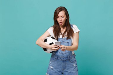 Cep telefonuyla tipik sms haber izole mavi turkuaz duvar arka plan üzerinde futbol topu ile meşgul genç kız futbol fan. İnsanlar duygular aile eğlence kavramı spor. Kopyalama alanı alay