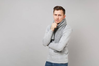 Gri kazak, eşarp koymak el pervane kadar gri duvar arka planda Studio izole çene üzerinde ciddi genç adam. Sağlıklı moda yaşam tarzı insanların samimi duygular soğuk sezon kavramı. Kopyalama alanı alay