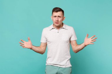 Ayakta, mavi turkuaz duvar arka planda Studio izole eller yayılan rahat kıyafetler şaşkın çapraşık genç adam portresi. İnsanlar samimi duygular yaşam tarzı kavramı. Kopyalama alanı alay