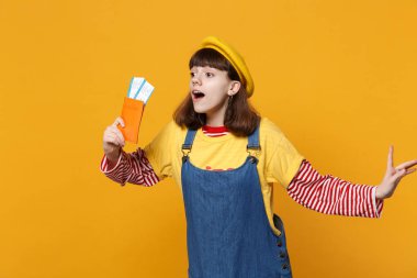 Hayran kız genç Fransız bere, bir kenara arıyorum, pasaport yatılı geçiş bileti üzerinde sarı arka plan izole denim sundress. İnsanlar samimi duygular, yaşam kavramı. Kopyalama alanı alay