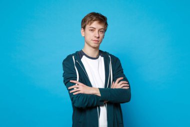 Rahat kıyafetler Studio mavi duvar arka plan üzerinde bir kenara katlanmış el ele tutuşarak ayakta seyir izole yakışıklı genç adam portresi. İnsanlar samimi duygular, yaşam kavramı. Kopyalama alanı alay