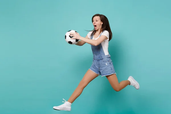 Shocked woman football fan cheer up support favorite team holding soccer ball jumping isolated on blue turquoise background. People emotions sport family leisure lifestyle concept. Mock up copy space