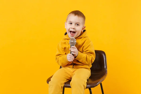 小乐趣的孩子男孩3 4岁在黄色衣服唱歌唱歌在话筒隔绝在明亮的橙色墙壁背景 孩子演播室画像 人们对儿童的生活方式概念 模拟复制空间 — 图库照片