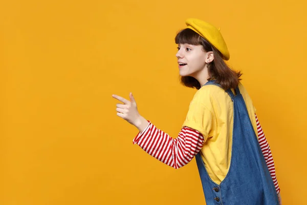 デニム サンドレス人差し指 Studio で黄色の背景に分離された脇のフレンチ ベレー帽で驚いて女の子ティーンエイ ジャーのサイドビュー の心から感情 ライフ スタイルのコンセプト コピー — ストック写真