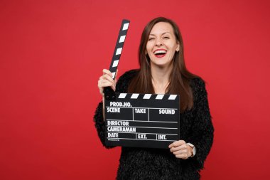 Siyah kürk kazak tutun klasik kara film Studio parlak kırmızı duvar arka plan üzerinde izole Klaket yapma genç kadın gülüyor. İnsanlar samimi duygular, yaşam kavramı. Kopyalama alanı alay