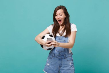 Sürpriz genç kız futbol fan istimal hareket eden telefon, mavi turkuaz duvar arka plan üzerinde izole sms mesajı yazarak futbol topu ile. İnsanların duyguları, spor aile eğlence kavramı. Kopyalama alanı alay