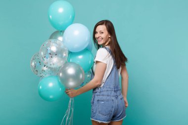 Geriye baktığımda, kutlama, izole mavi turkuaz arka plan üzerinde renkli hava balonları bekletme denim giyim gülümseyen genç kadın dikiz geri. Doğum günü tatil partisi, insanların duyguları kavramı