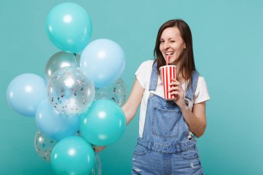 Plastik bardak kola veya renkli hava balonları ile kutluyor soda tutan kot elbise genç kadında yanıp sönen mavi turkuaz arka plan üzerinde izole. Doğum günü tatil partisi, insanların duyguları kavramı