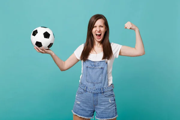 Strong screaming woman football fan cheer up support favorite team with soccer ball showing biceps, muscles isolated on blue turquoise wall background. People emotions, sport family leisure concept